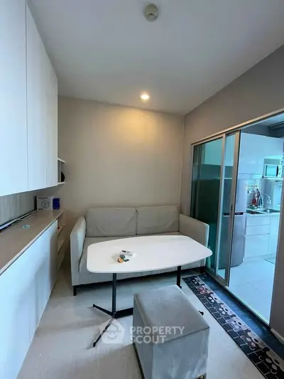 Cozy living room with modern furniture and sliding glass doors leading to a sleek kitchen area.