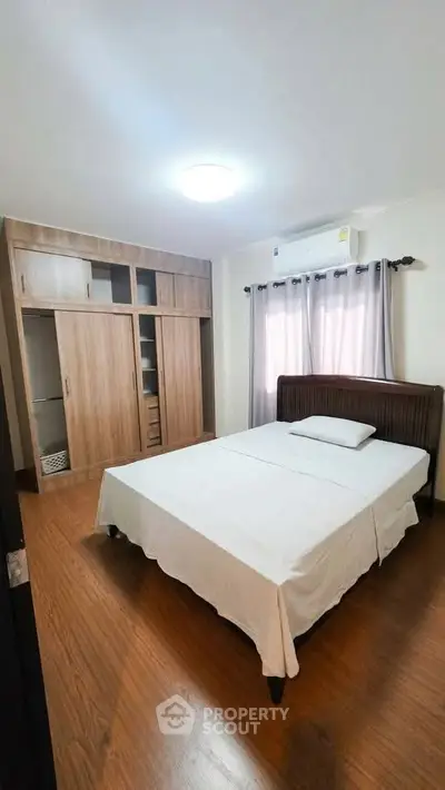 Spacious bedroom with wooden flooring and built-in wardrobe, perfect for cozy living.
