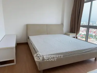 Spacious bedroom with large window offering stunning city views