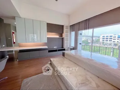 Spacious modern bedroom with large windows and scenic view, featuring sleek built-in storage and elegant wood flooring.