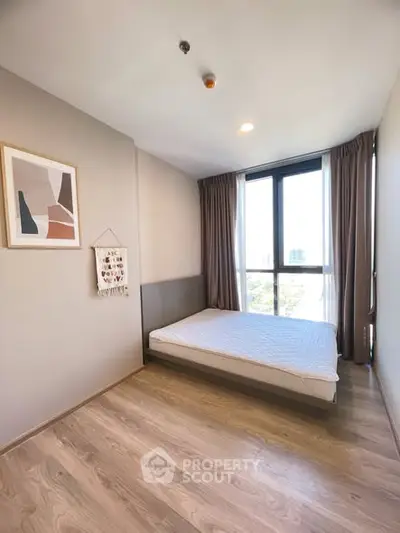 Modern minimalist bedroom with large window and stylish decor in a high-rise apartment.