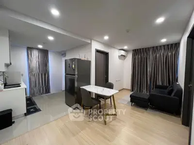 Modern open-layout living room with kitchen and dining area, featuring sleek furniture and ambient lighting.
