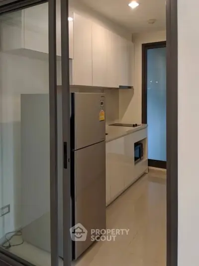 Modern kitchen with sleek cabinetry and stainless steel fridge in compact layout.