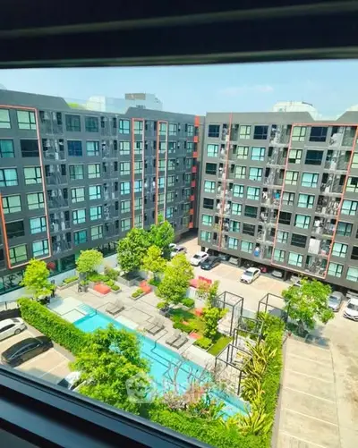 Modern apartment complex with pool and lush greenery, offering urban living with leisure amenities.