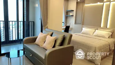 Modern studio apartment with cozy bed and stylish sofa near a balcony with city view.