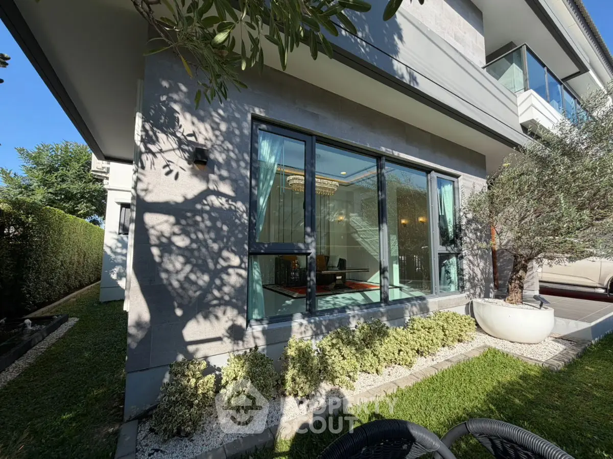 Modern luxury home exterior with large windows and lush garden, showcasing elegant architectural design.