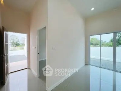 Spacious modern interior with high ceilings and large windows offering natural light and garden view.