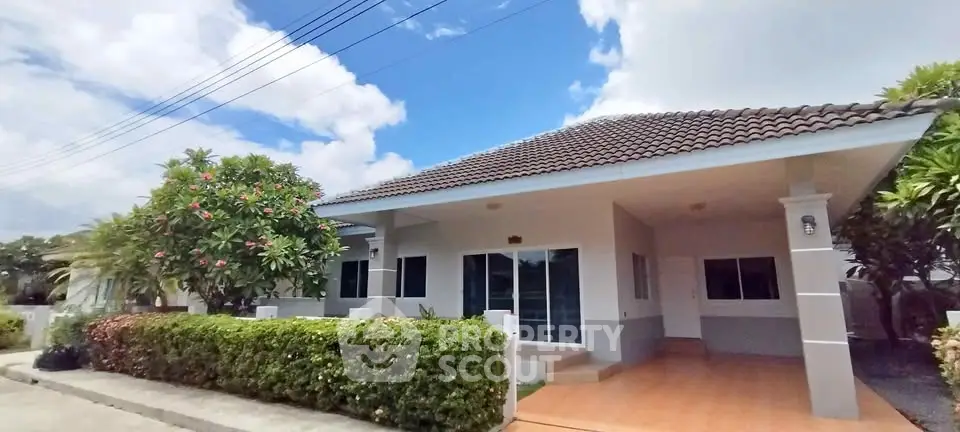 Charming single-story house with tiled roof and lush garden in serene neighborhood.