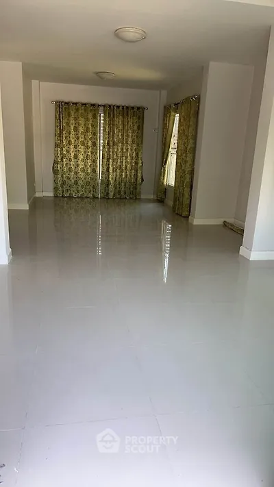 Spacious empty room with glossy tiled floors and floral curtains, ideal for customization.
