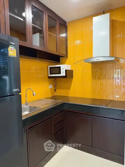 Modern kitchen with vibrant orange tiles and sleek dark cabinetry