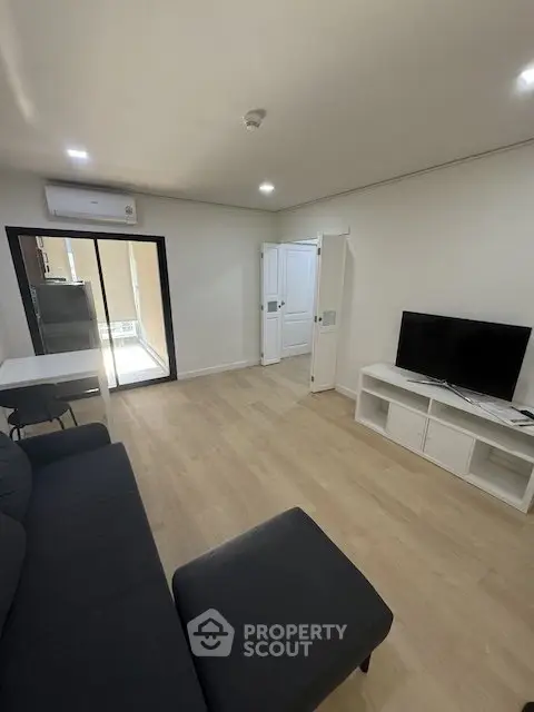 Modern living room with sleek furniture and balcony access in a stylish apartment.