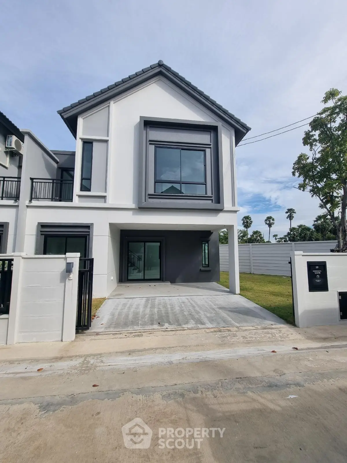 Modern two-story house with driveway and lush green surroundings
