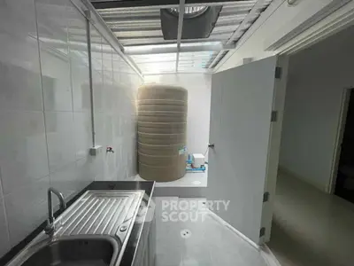 Compact utility area with sink and large water tank in modern home.