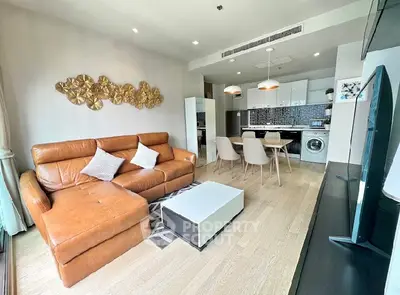 Modern living room with open kitchen, leather sofa, and stylish decor in a contemporary apartment.