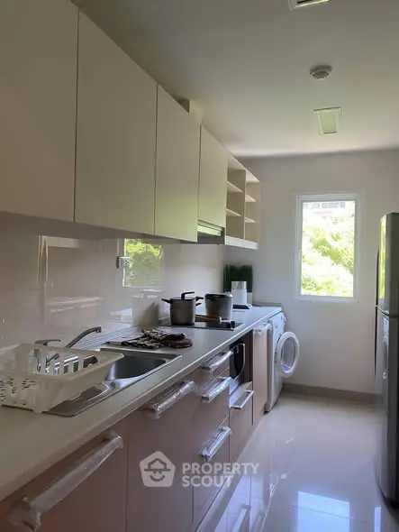 Modern kitchen with sleek cabinetry, appliances, and natural light from window.