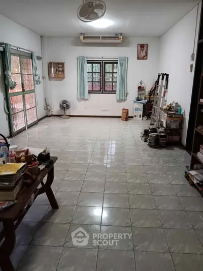 Spacious living room with tiled flooring and large windows, perfect for natural light.