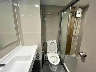 Modern bathroom with sleek design, featuring a glass shower enclosure and contemporary fixtures.