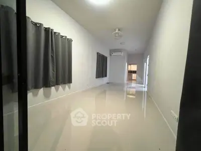 Spacious empty room with glossy tiled floor and modern air conditioning.