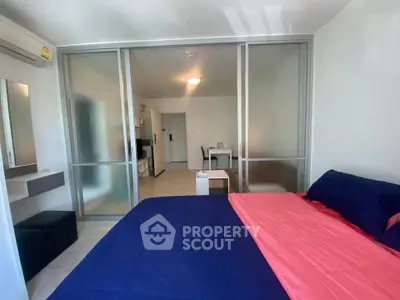 Modern bedroom with sliding glass doors and vibrant bedding in a stylish apartment.