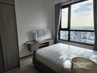 Modern high-rise bedroom with expansive city views through large windows, featuring a plush bed and minimalist decor for a serene urban retreat.