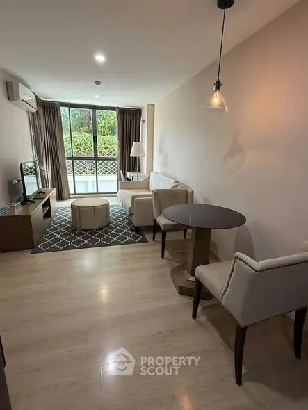 Spacious living room with modern furniture and large window offering garden view.