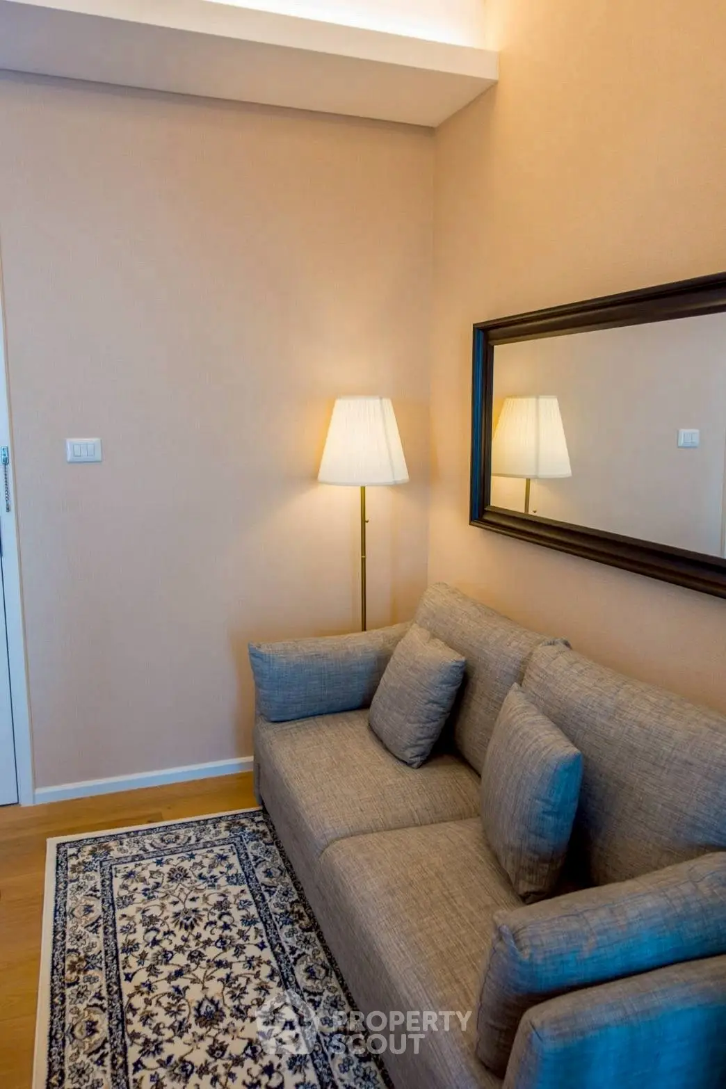 Cozy living room with elegant sofa, stylish lamp, and decorative mirror enhancing the warm ambiance.