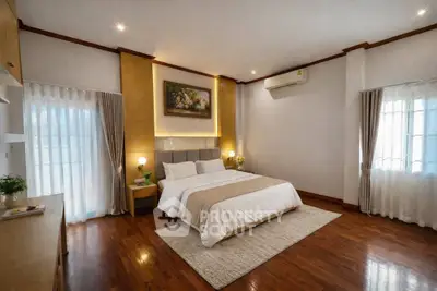 Spacious bedroom with elegant decor and hardwood floors, featuring a cozy bed and natural light.