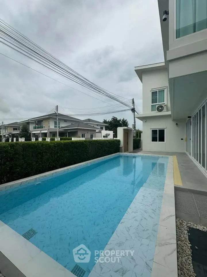 Modern home with private pool and lush greenery in a serene neighborhood.