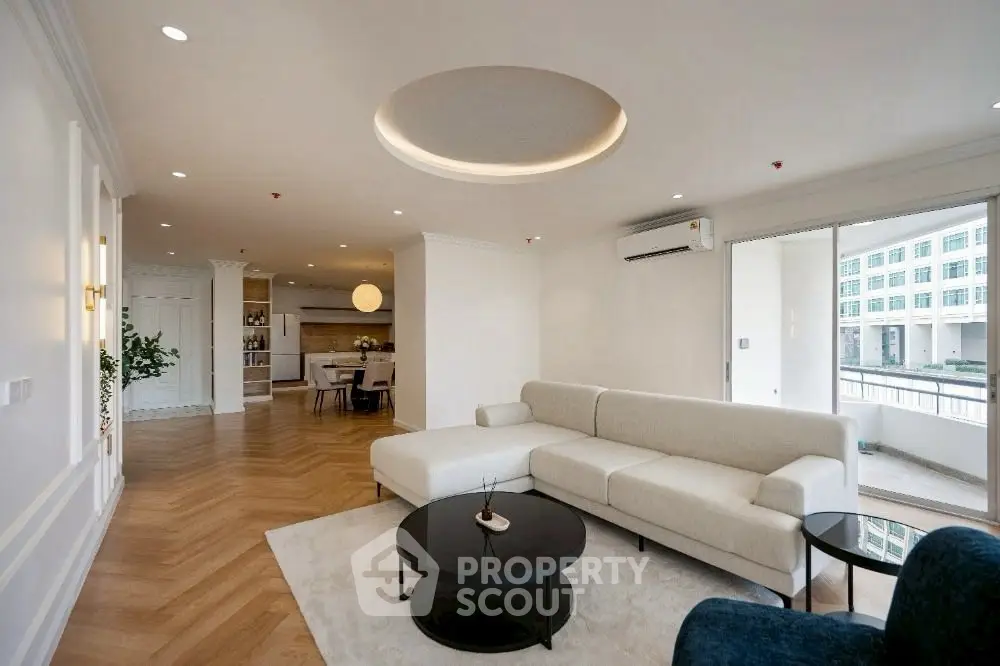 Spacious modern living room with elegant decor and open layout, featuring a large white sofa and stylish coffee tables.