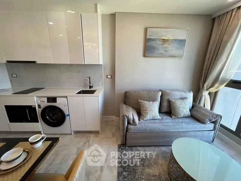 Modern living room with sleek kitchen, featuring a washing machine and elegant decor.