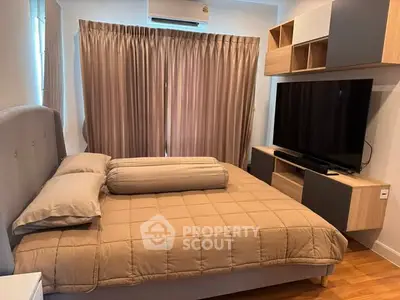 Cozy bedroom with modern furniture and large TV, perfect for relaxation.