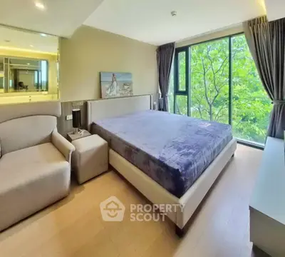 Spacious bedroom with large window and modern furnishings, offering a serene view of lush greenery.