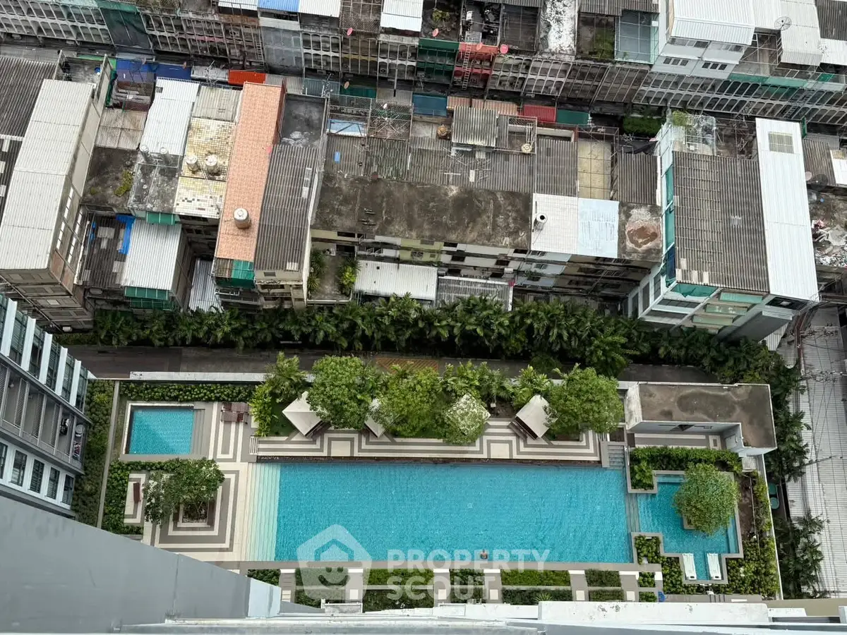 Stunning aerial view of modern residential pool with lush greenery and urban backdrop.