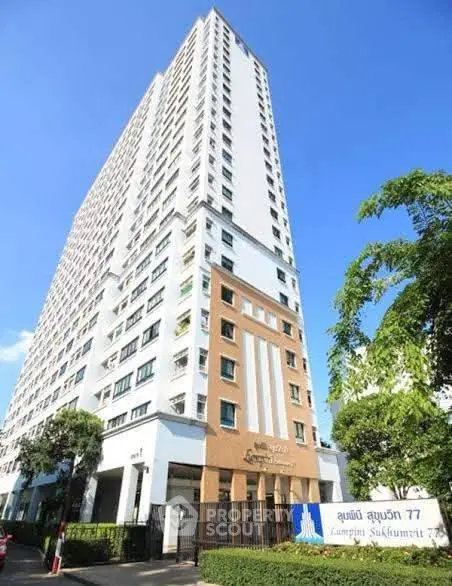 Modern high-rise condominium building with clear blue sky and lush greenery.