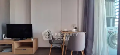 Cozy living area with TV, dining set, and washing machine near balcony.