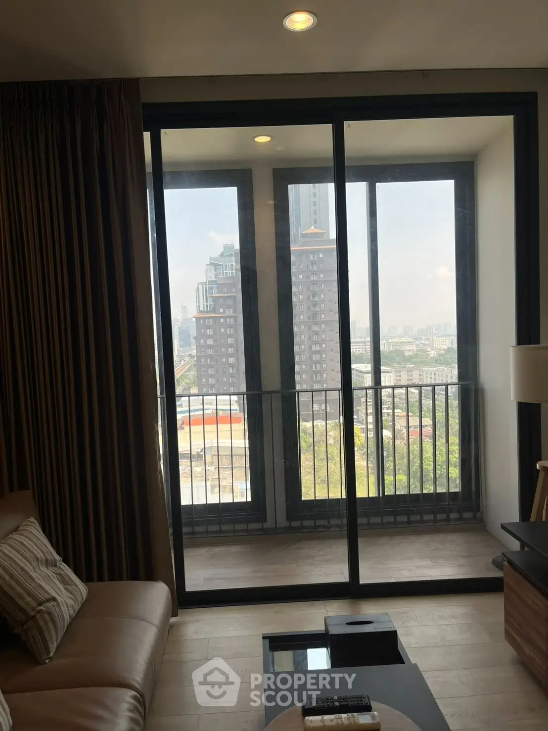 Modern living room with balcony offering stunning city view, featuring cozy seating and elegant decor.
