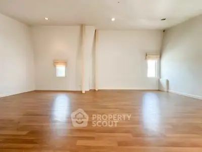 Spacious empty room with wooden flooring and white walls, perfect for customization.