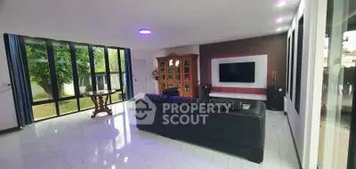 Spacious modern living room with large windows and sleek black furniture