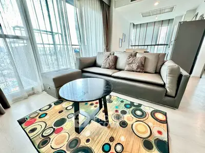 Modern living room with stylish decor and large windows offering city views.