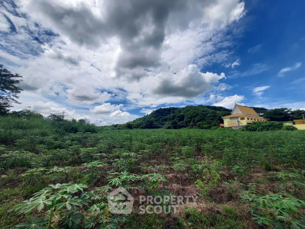 Expansive green field with scenic mountain view under a vibrant blue sky, perfect for development.