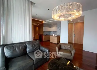 Luxurious modern living room with elegant chandelier and leather furniture in upscale apartment.