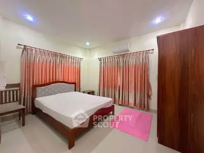 Spacious bedroom with elegant curtains and air conditioning, featuring a cozy bed and wooden wardrobe.