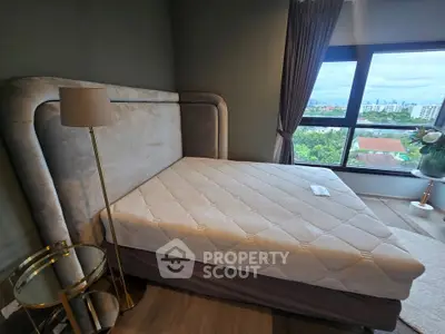 Spacious bedroom with large window offering stunning city views, featuring a luxurious bed and elegant decor.