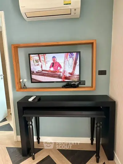 Stylish living room with modern TV setup and elegant console table under air conditioning unit.