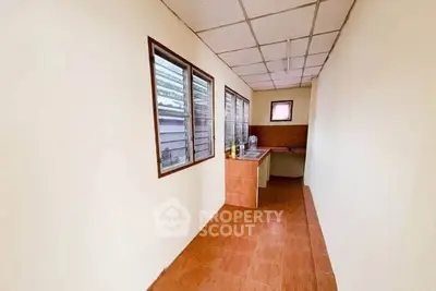 Narrow kitchen with tiled floor and counter, featuring large windows for natural light.
