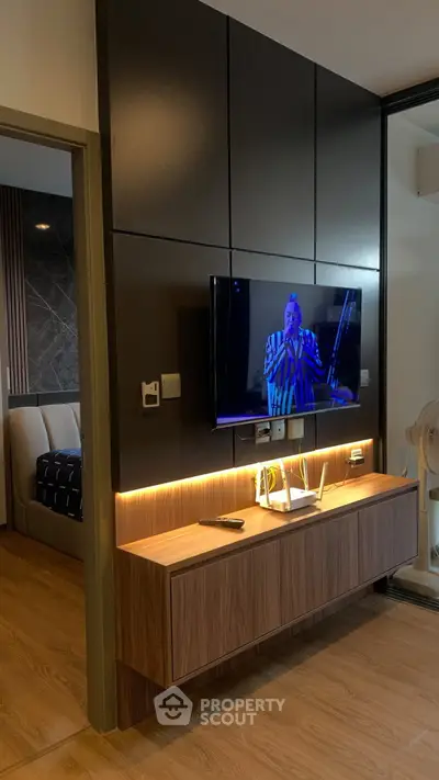 Modern living room with wall-mounted TV and stylish wooden console, adjacent to a cozy bedroom.