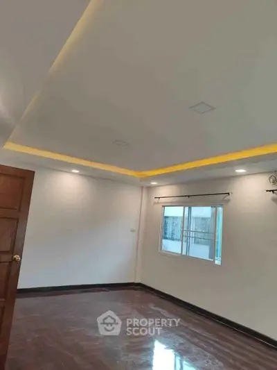 Spacious empty room with elegant ceiling lighting and polished wooden floor