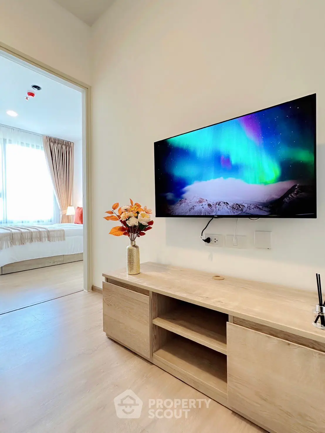 Modern living room with wall-mounted TV and view into cozy bedroom