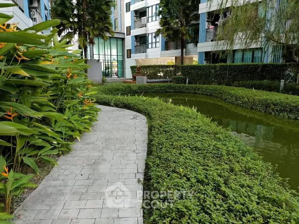 Lush garden view with modern apartment building and serene pond