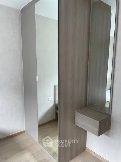 Modern bedroom with sleek mirrored wardrobe and minimalist design.